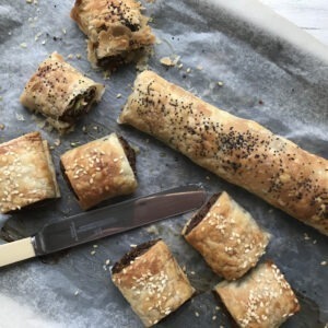 Vegan sausage rolls on tray with knife
